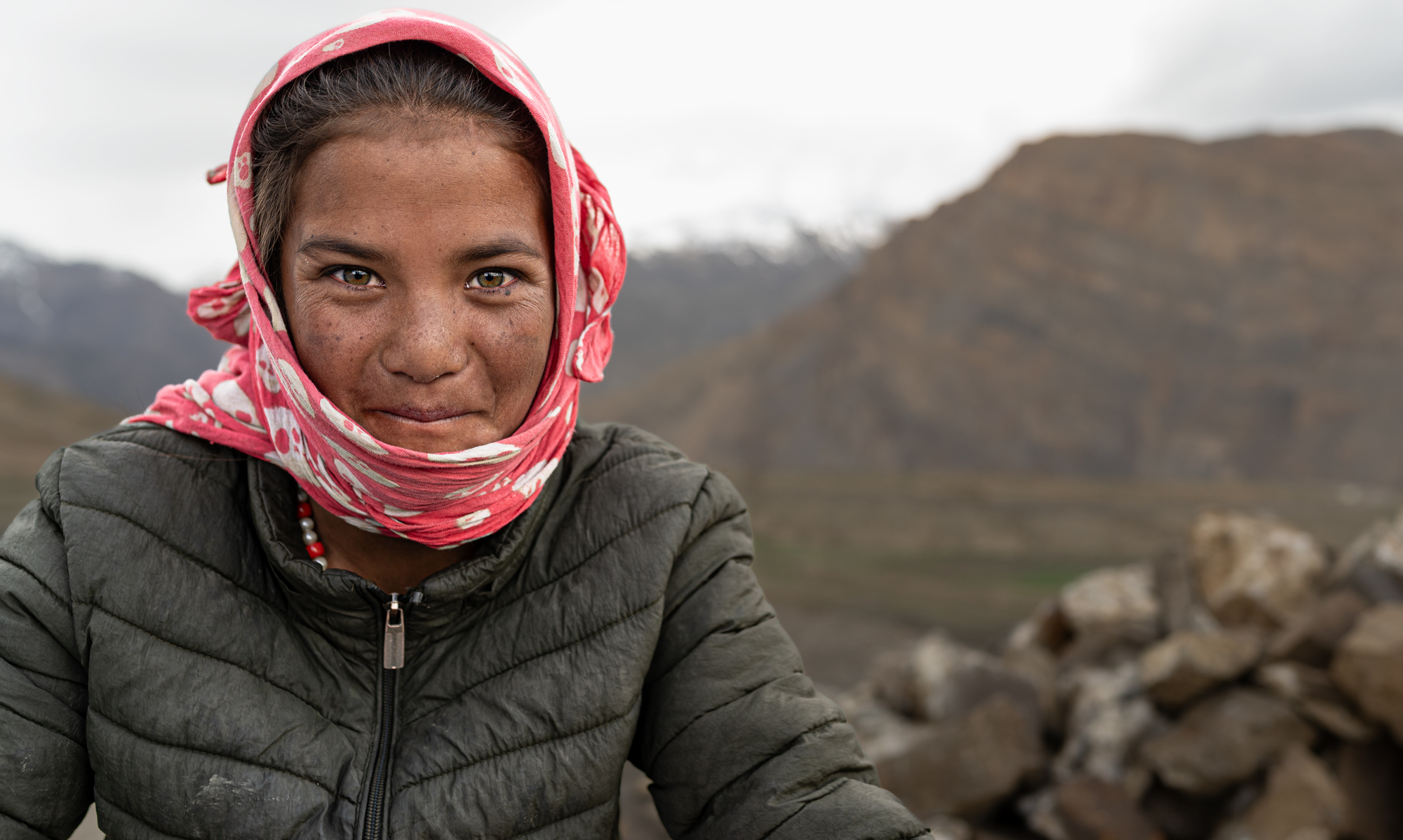 Photo of a Spitian girl with grey-green-brown eyes staring into the camera mischeviously.